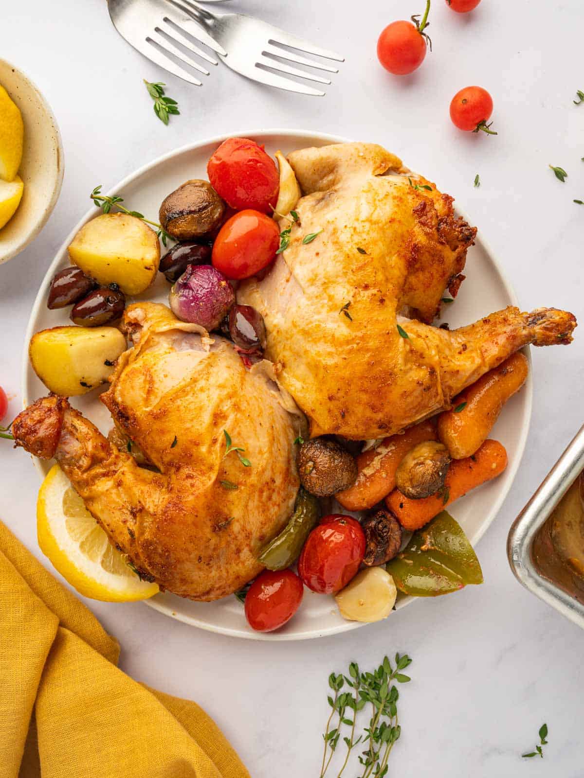 Roasted chicken quarters on a plate with veggies.