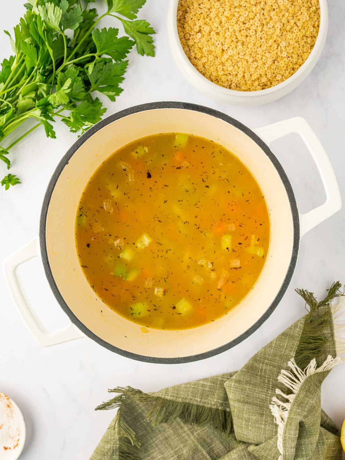 Broth and vegetables are cooked in a dutch oven.