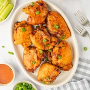 A platter of baked chicken thighs basted with buffalo sauce.