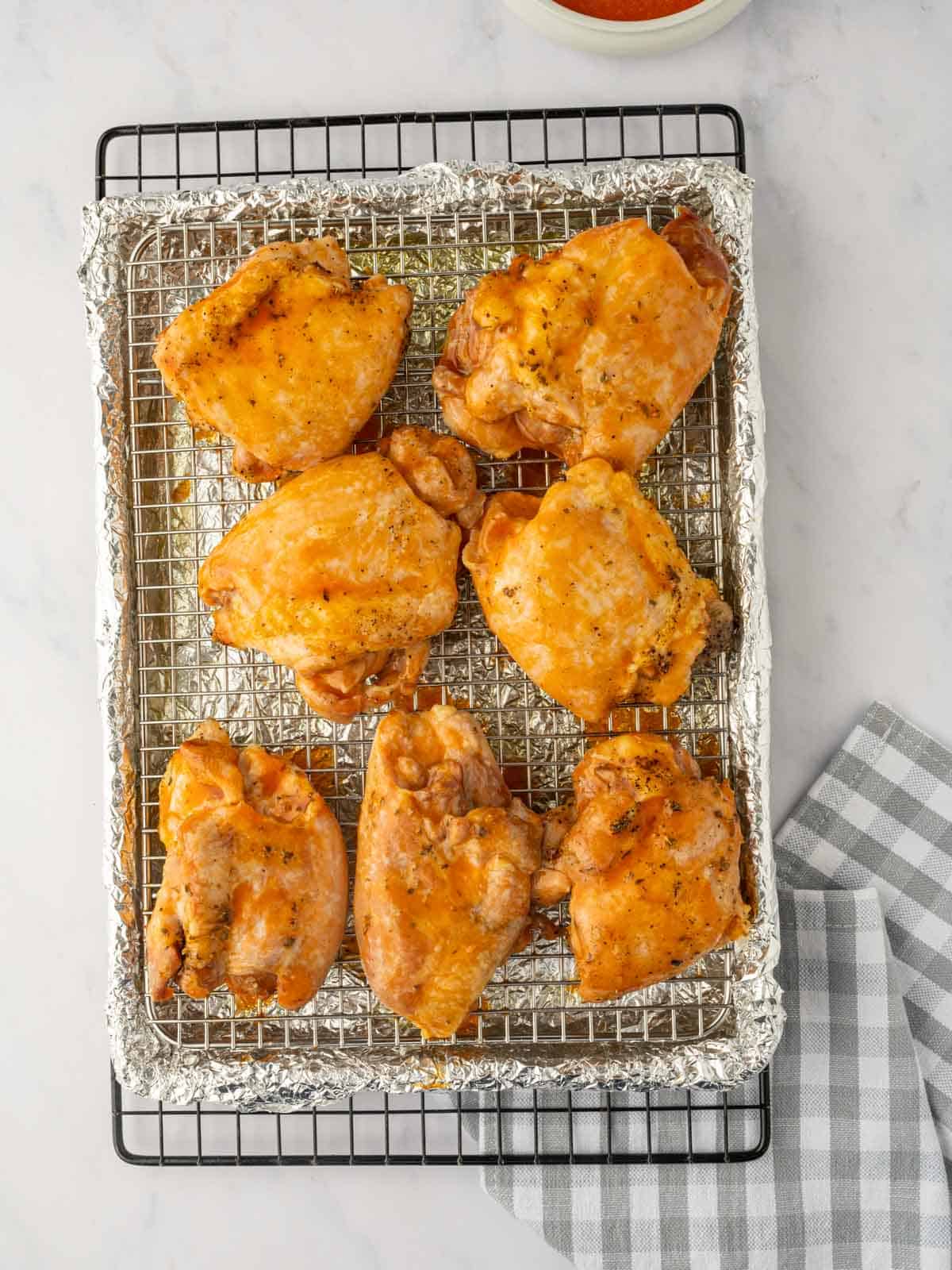 Baked chicken thighs are brushed with buffalo sauce.