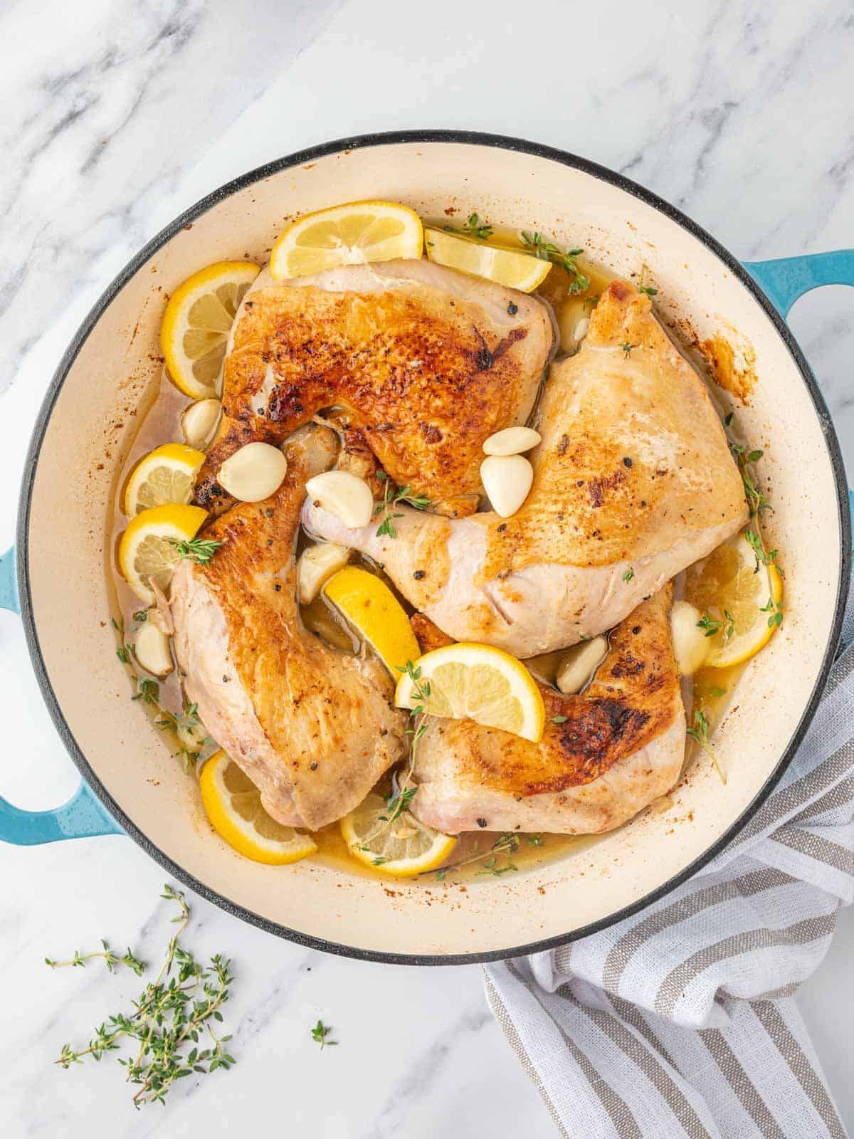 braised chicken legs in a skillet with aromatics.