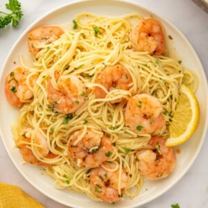 A plate with a serving of shrimp and pasta.