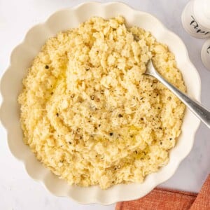 A spoon rests in a white bowl of pastina pasta.