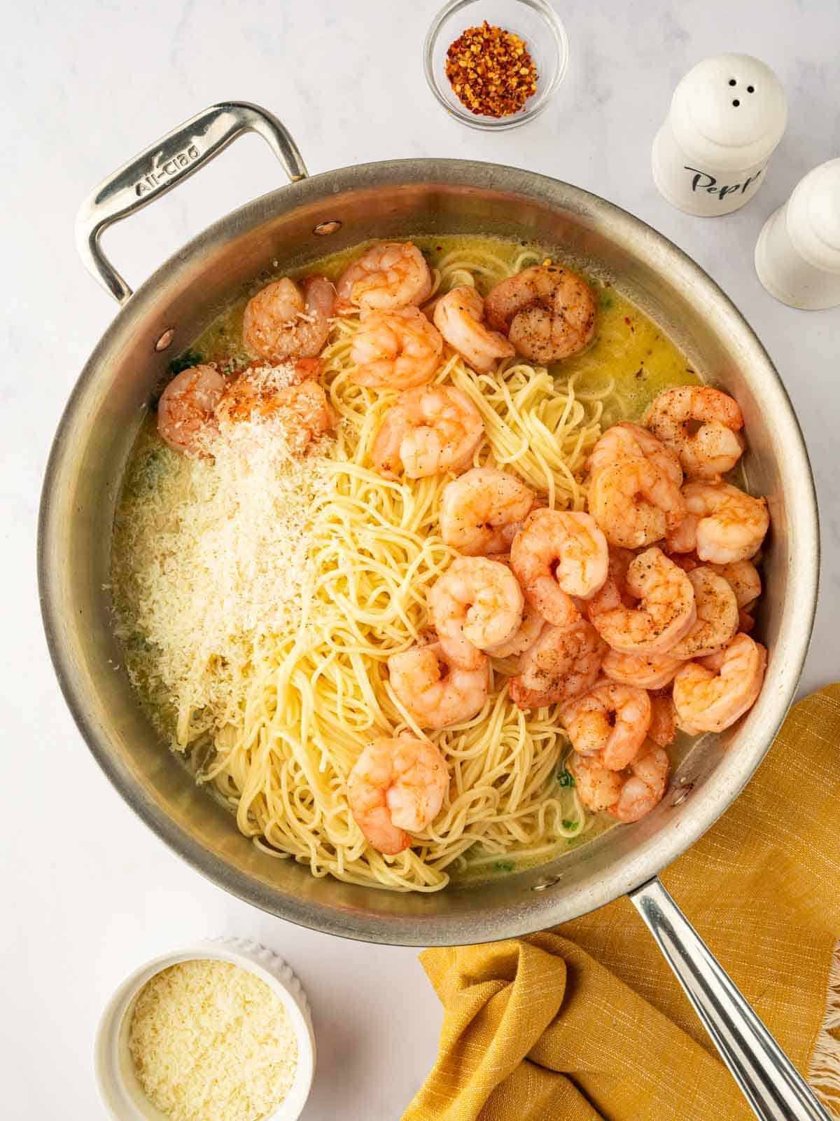 Process of mixing shrimp with pasta and cheese.