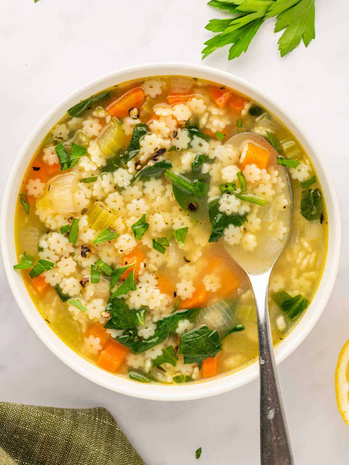 A spoon rests in a bowl of pastina soup.