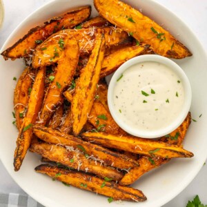 A bowl of sweet potato wedges with dipping sauce.