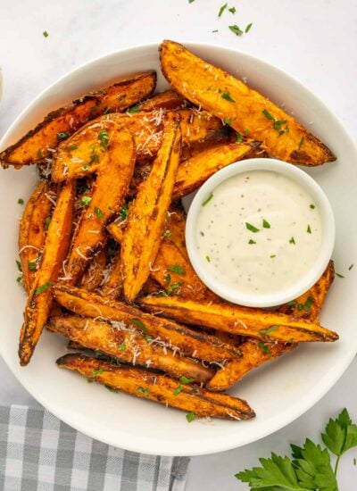 A bowl of sweet potato wedges with dipping sauce.