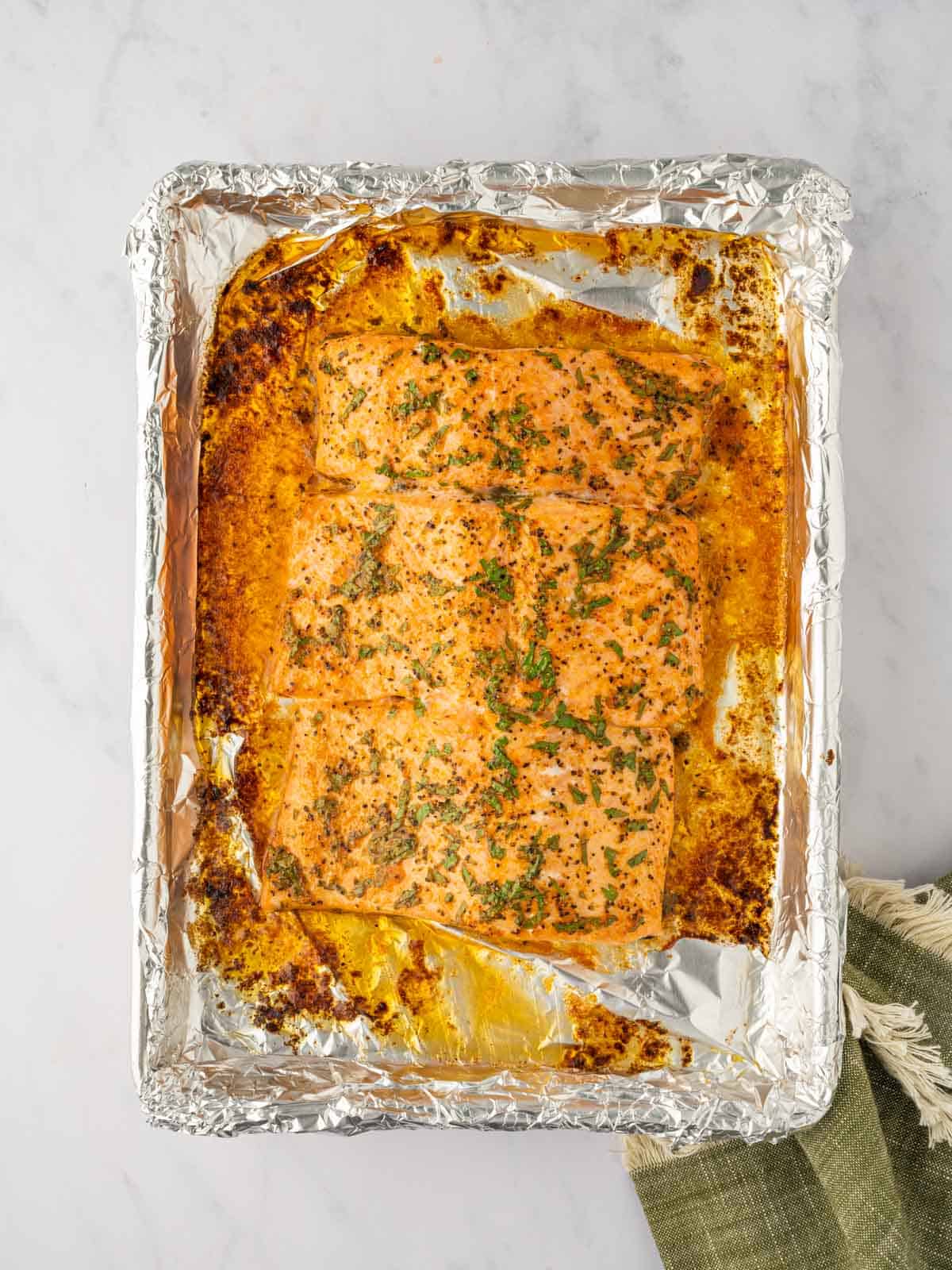 Baked salmon on a foil lined tray.