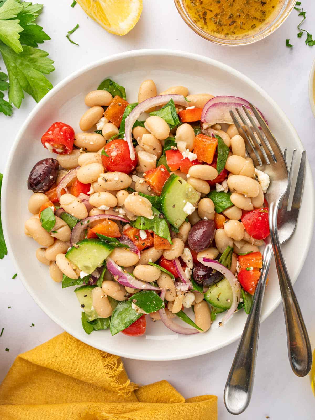A bowl of Greek Bean Salad with two forks resting on the side.