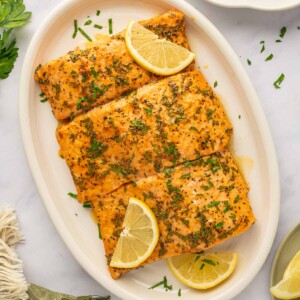 A tray of salmon with lemon pepper sauce.
