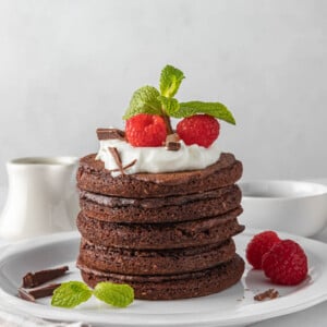 A stack of chocolate pancakes on a white plate.