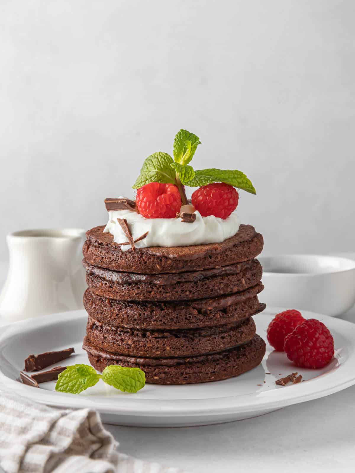 A stack of chocolate pancakes on a white plate.