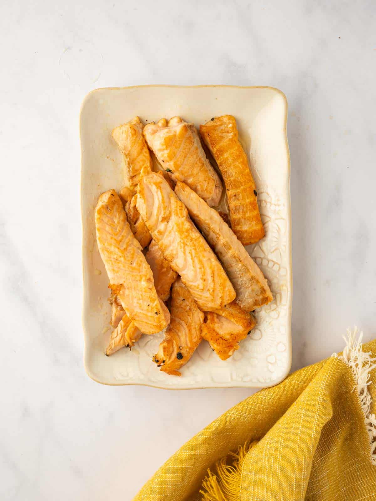 Cook strips of salmon are on a plate.