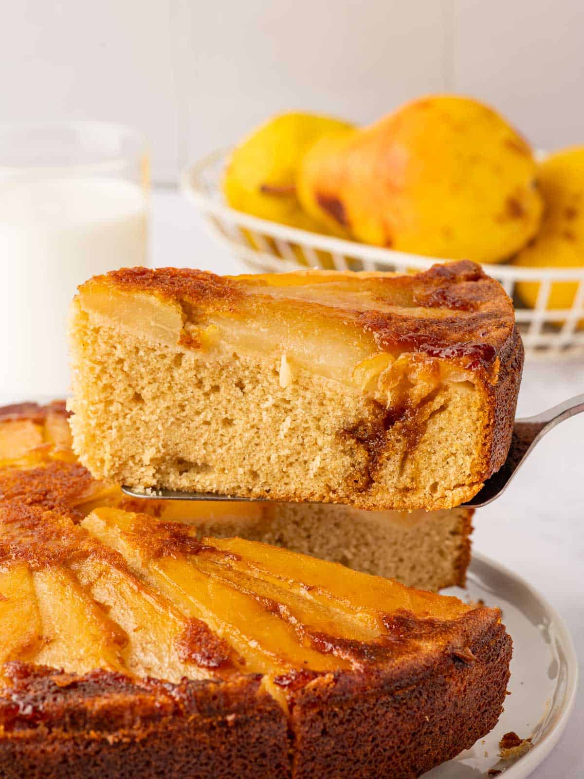 A piece of cake is lifted above the rest of the pear cake.
