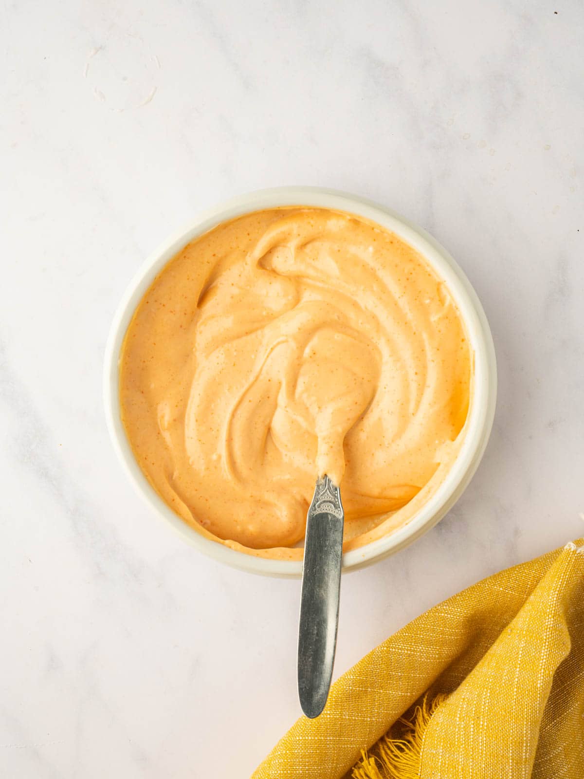 A spicy mayo sauce is mixed in a small bowl.