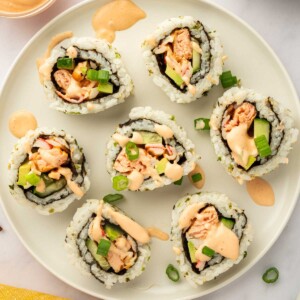 Pieces of spicy salmon sushi roll rest on a plate.