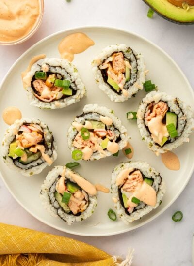Pieces of spicy salmon sushi roll rest on a plate.