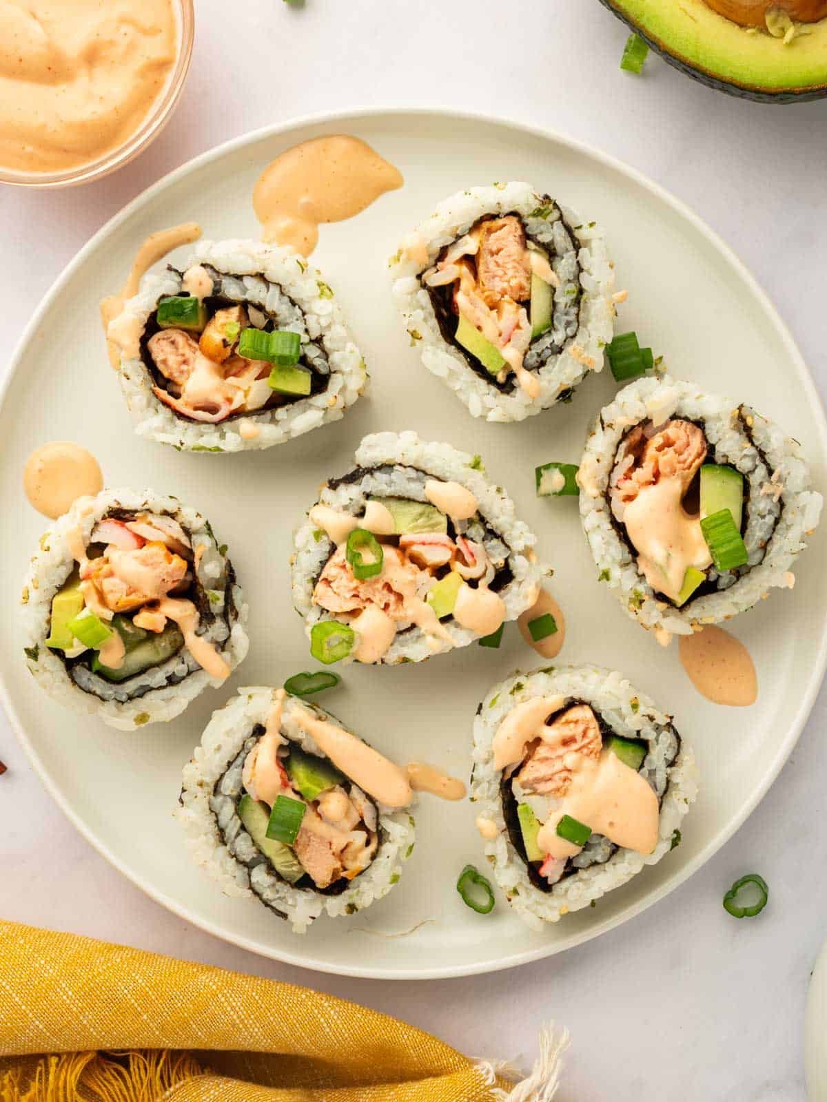 Pieces of spicy salmon sushi roll rest on a plate.