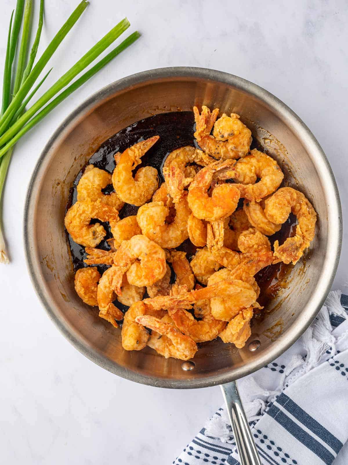 Crispy shrimp in a skillet about to be tossed with honey sauce.