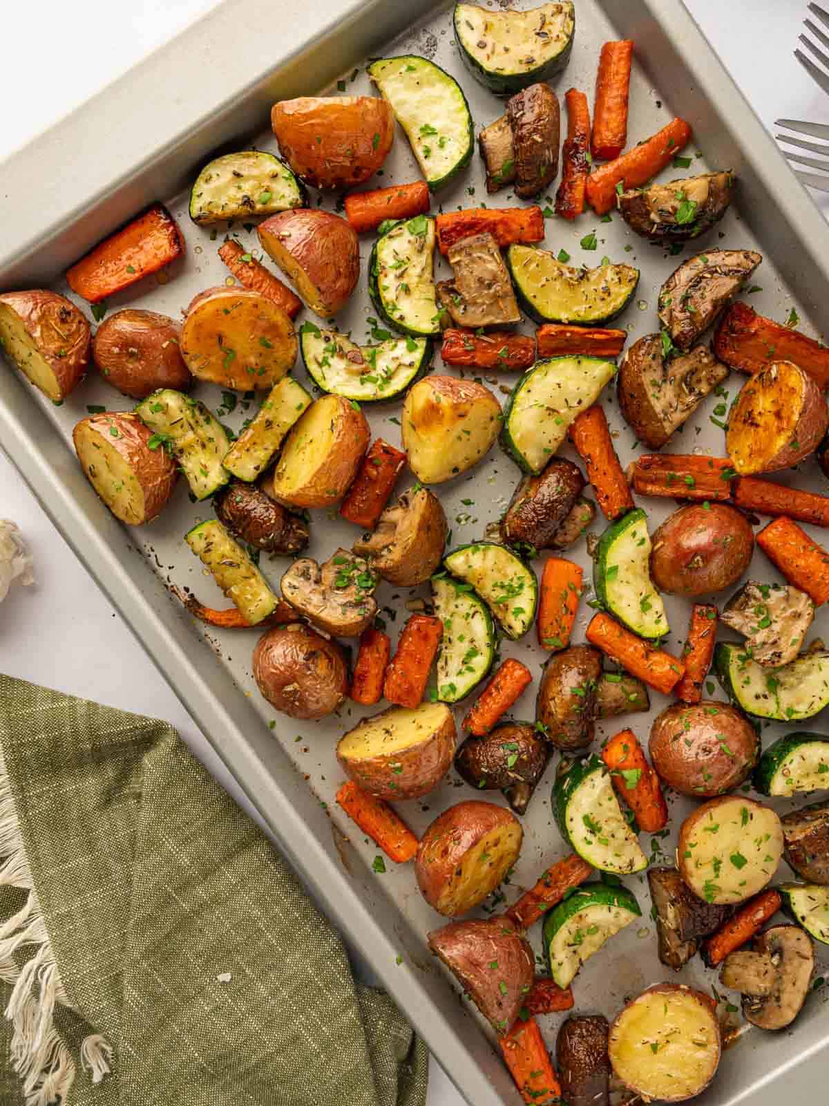 Roasted vegetables are on a baking tray.