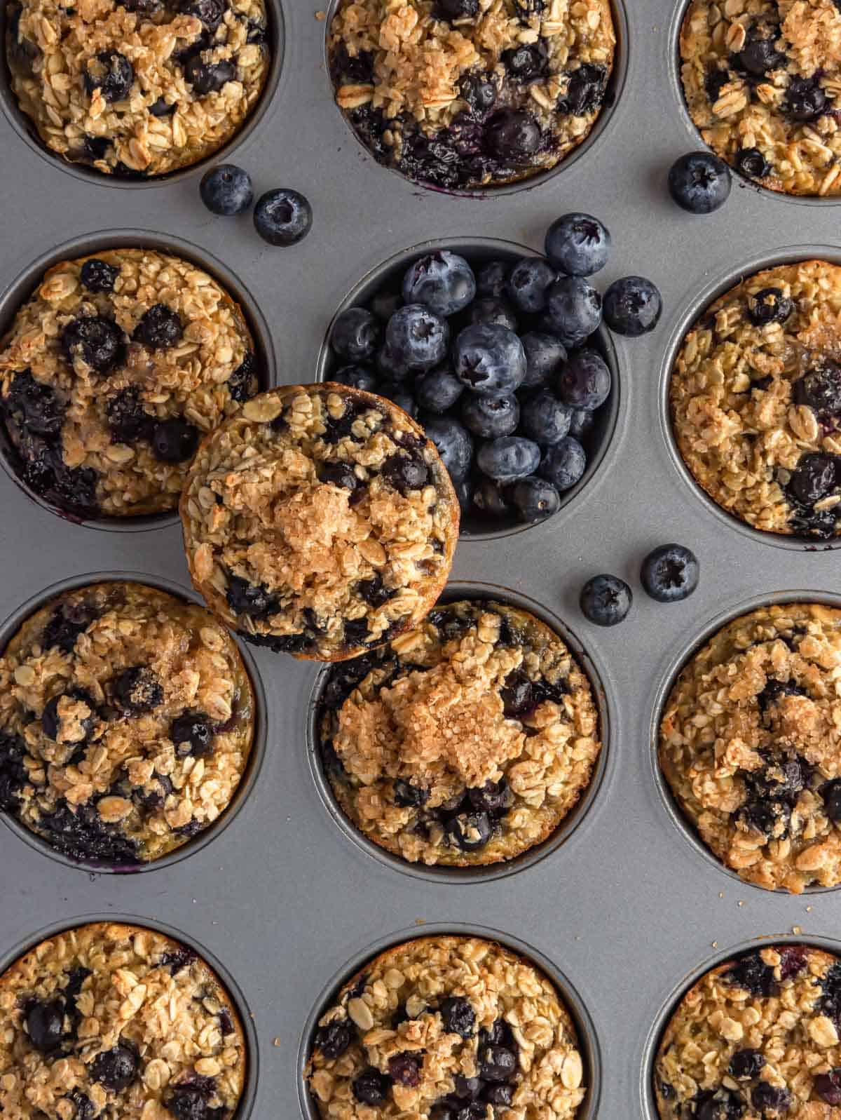 Cooked blueberry oatmeal cups on a tray with blueberries.