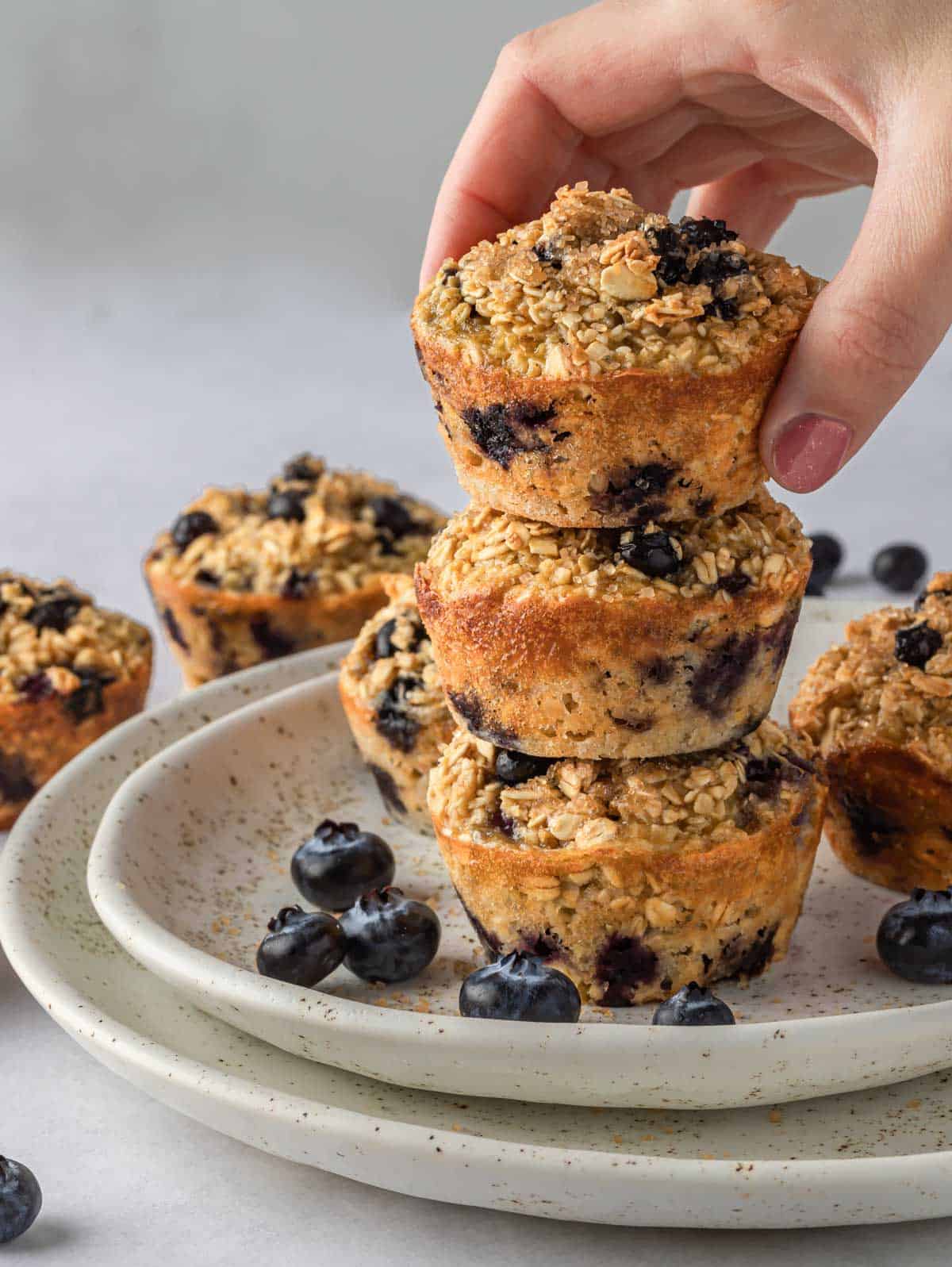 A hand places a blueberry cup on a stack.