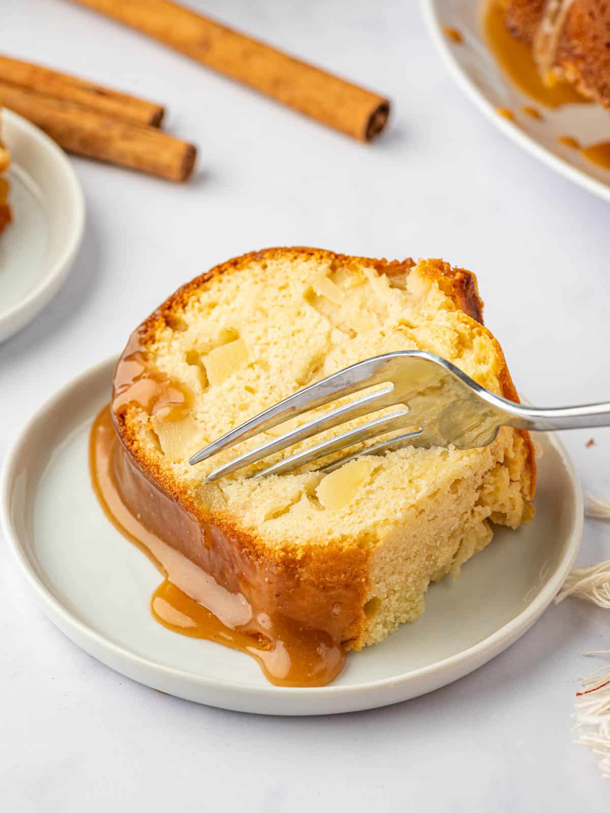 A fork slices into a piece of pear cake.