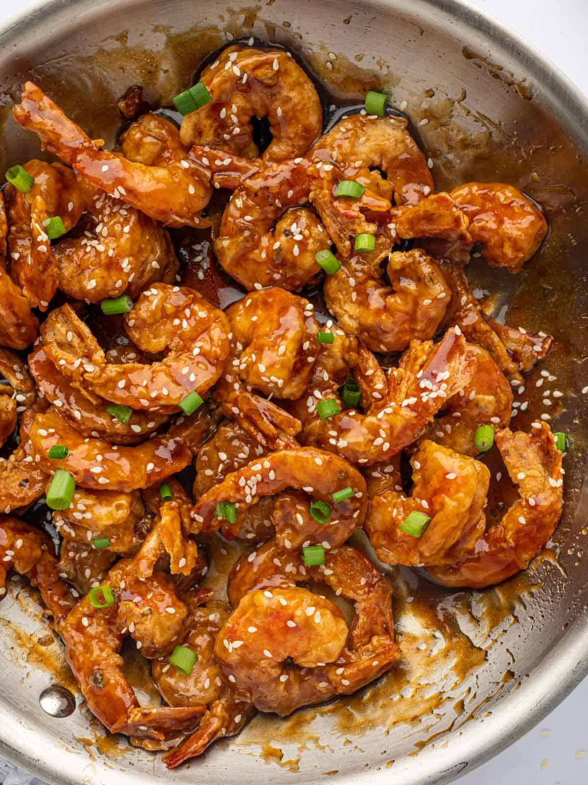 Shrimp tossed in a honey sauce in skillet.