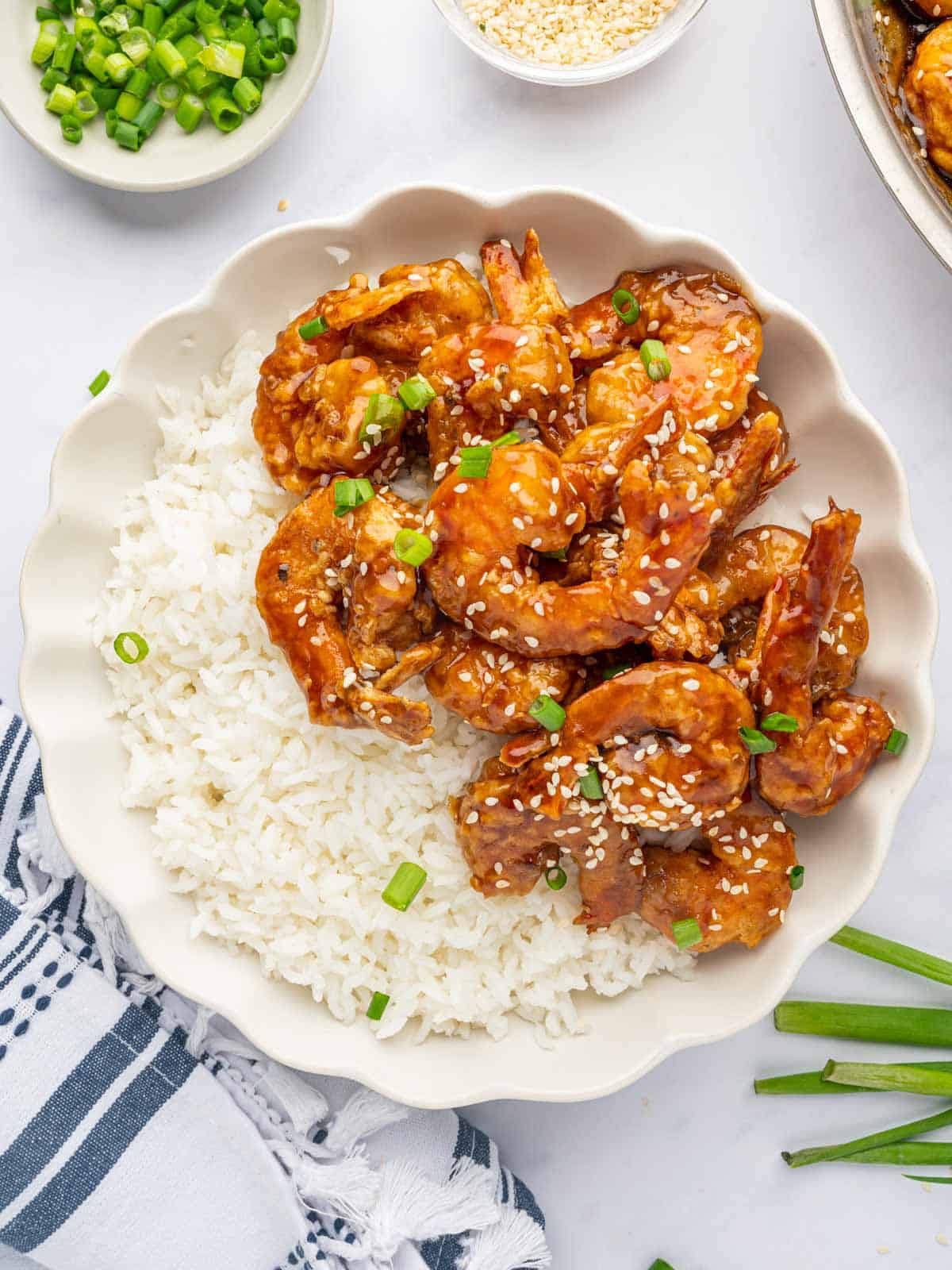 Honey fried shrimp on a white place with white rice.
