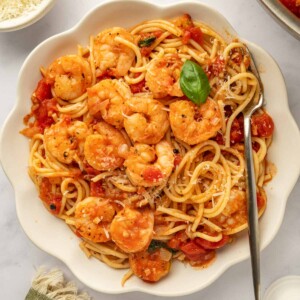 A bowl of pasta topped with sauteed shrimp.