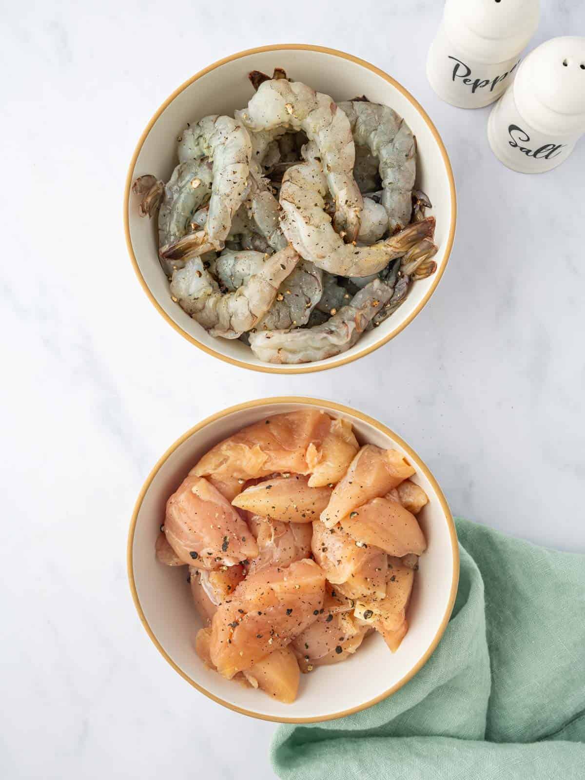 Raw shrimp and chicken are seasoned with salt and pepper.
