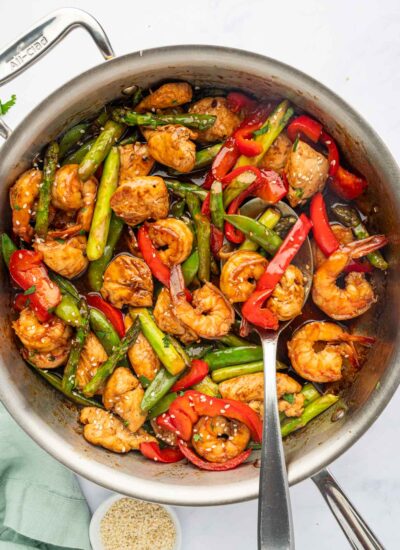 A spoon serves stir fry with chicken and shrimp.
