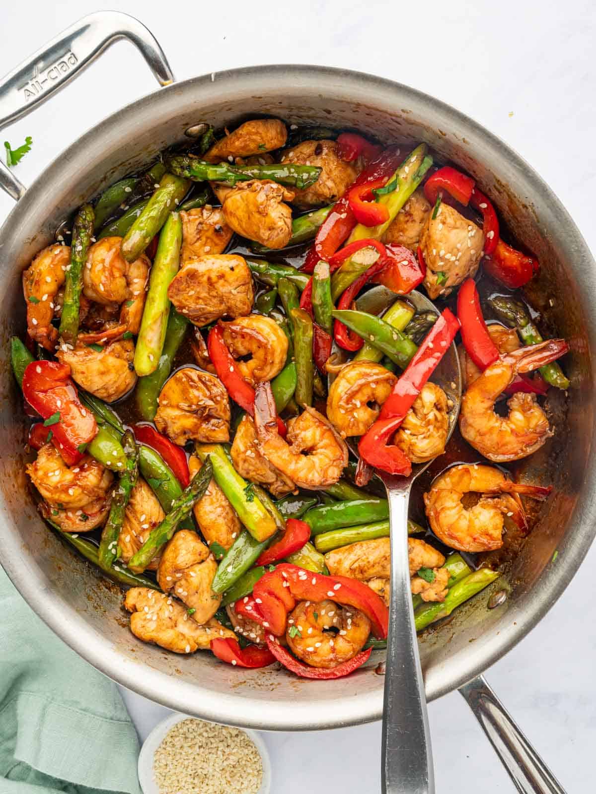 A spoon serves stir fry with chicken and shrimp.