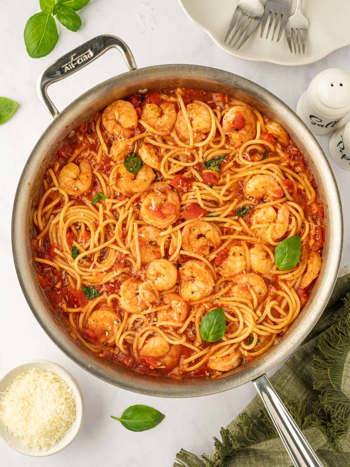 A skillet with spaghetti and shrimp in red sauce.
