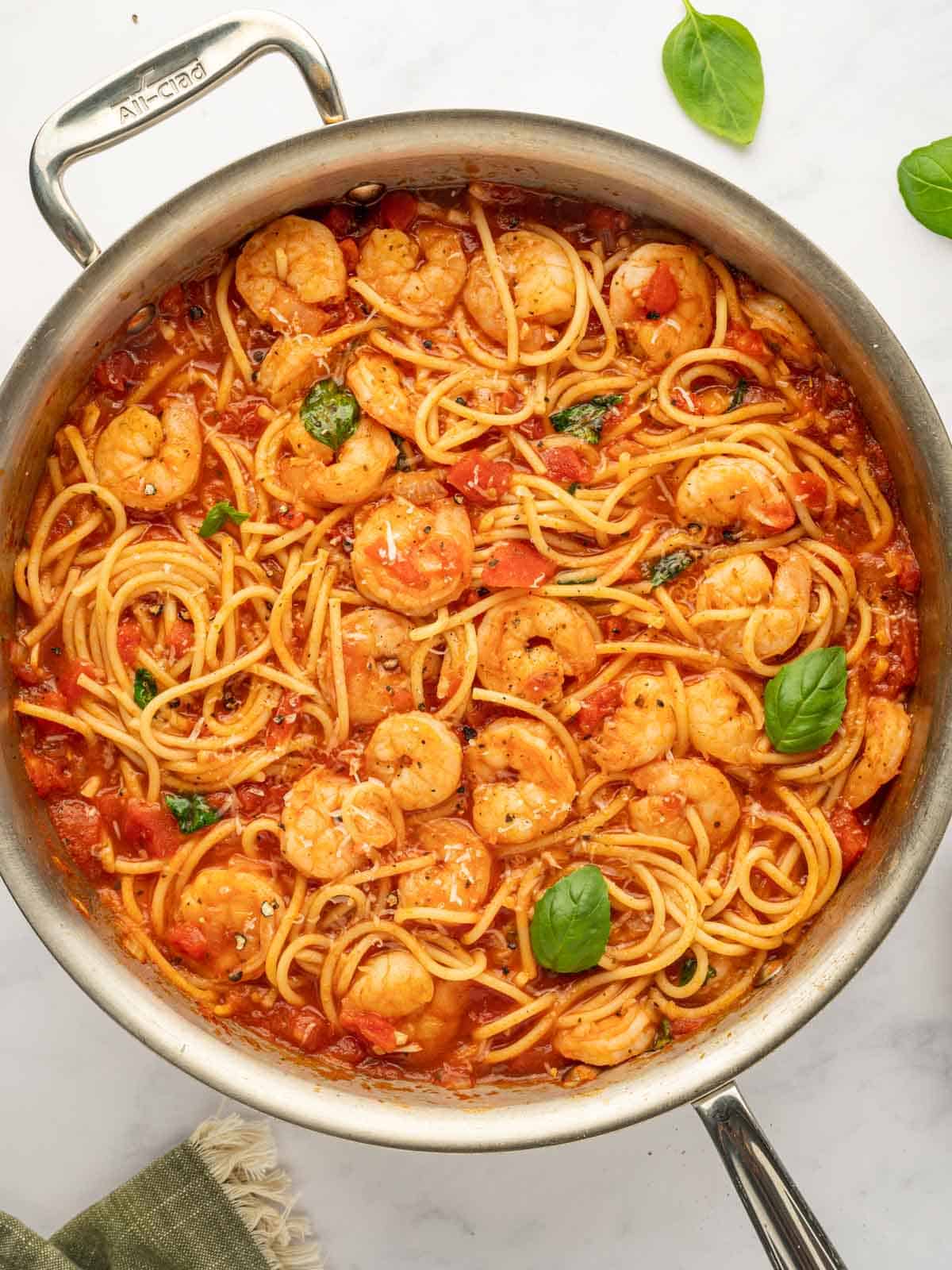 Shrimp spaghetti garnished with basil in a skillet.