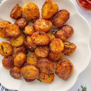 Crunchy, golden potatoes are on a white platter.