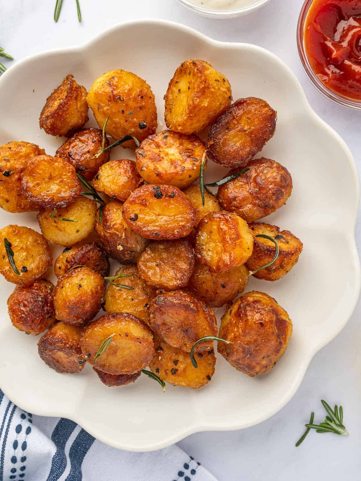 Crunchy, golden baby potatoes are on a white platter.