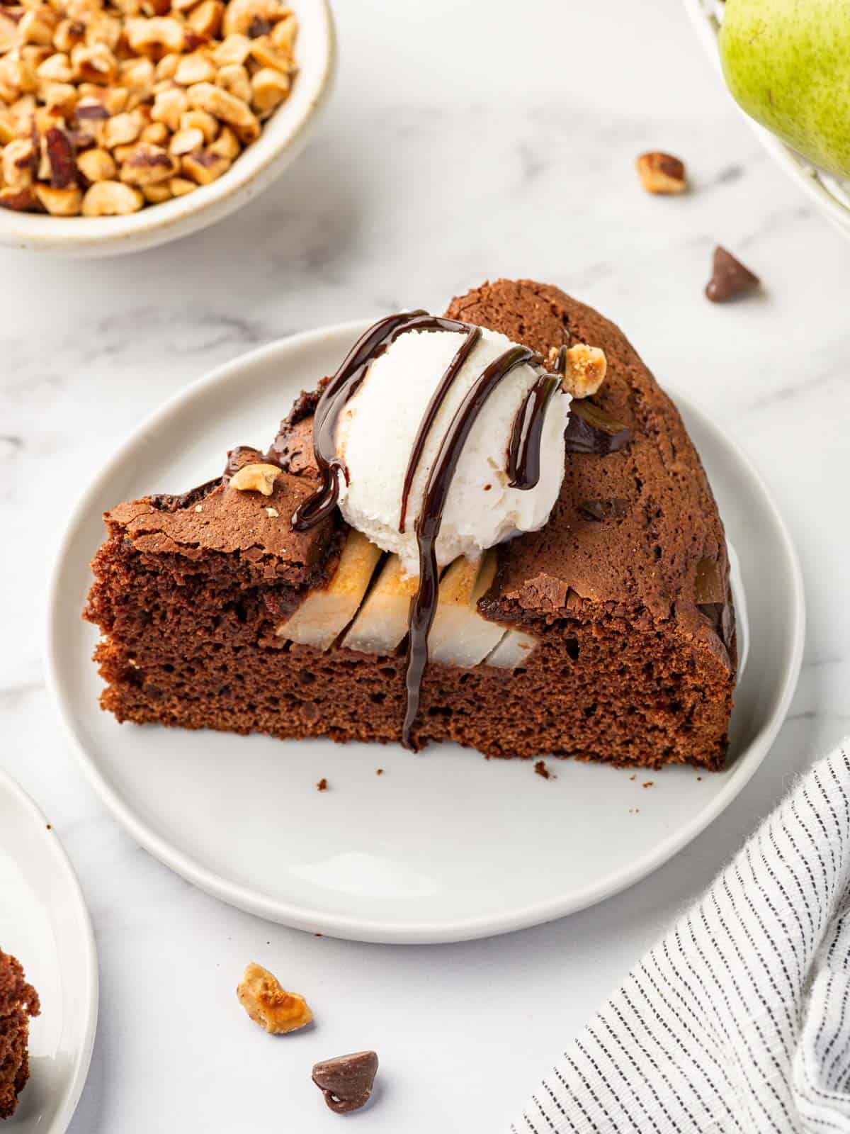 A slice of pear cake topped with ice cream and chocolate drizzle.