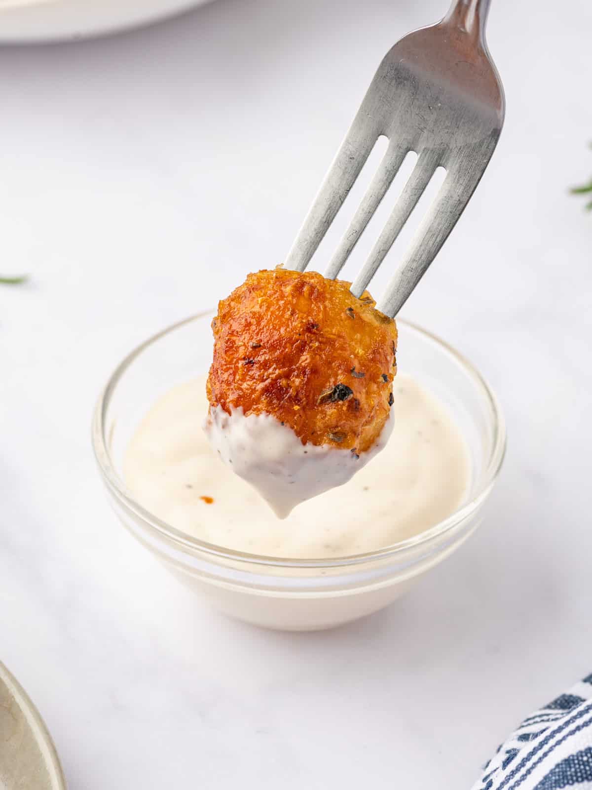 Baby Roasted potato is dipped in a creamy sauce.