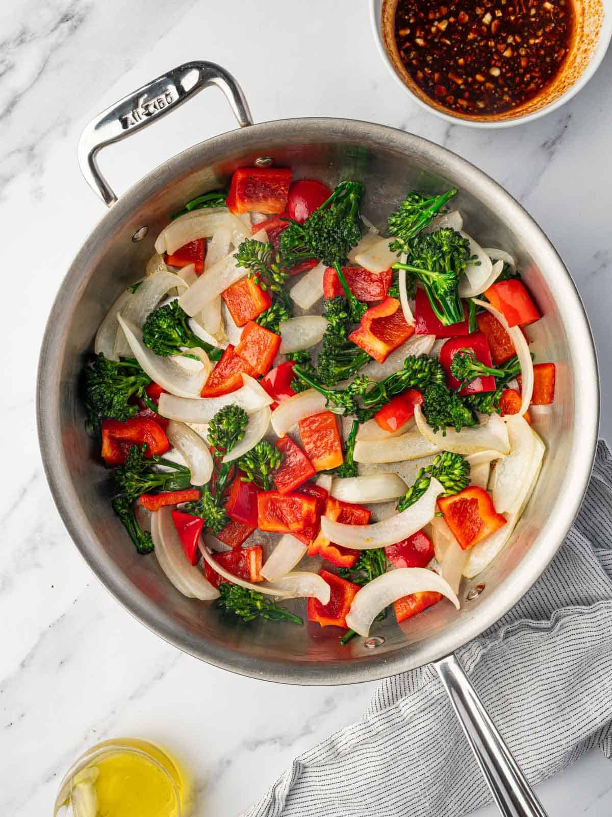 Fresh vegetables are stirfried in a skillet.