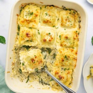 A spoon serves up a section of ravioli pasta bake.