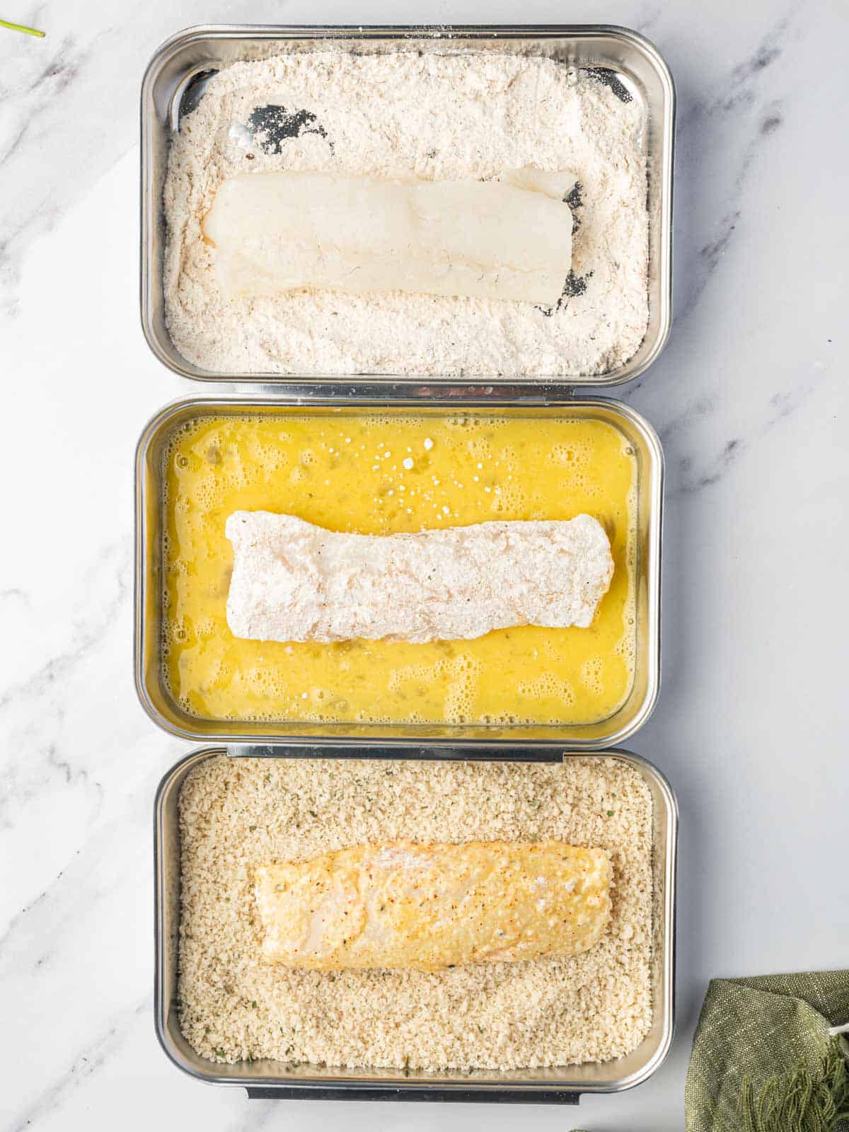 Process of dredging cod filets in flour, egg and breadcrumbs.