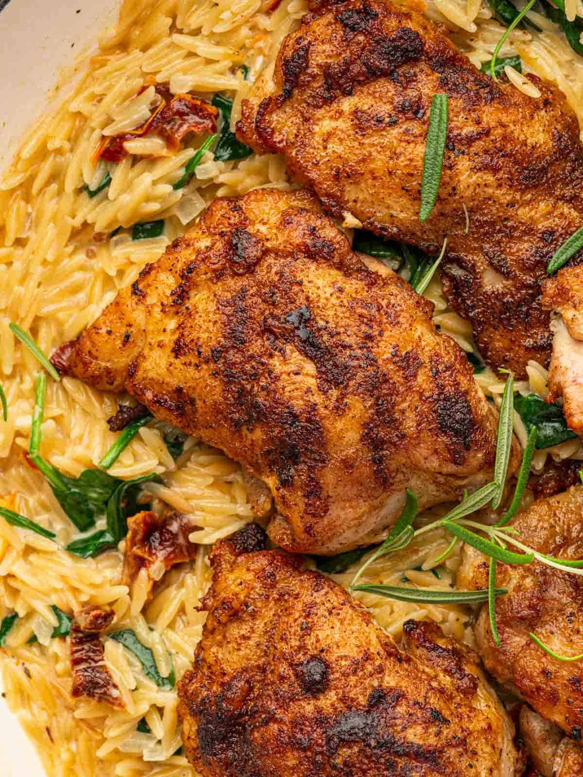 Closeup of cajun chicken thighs with orzo pasta.