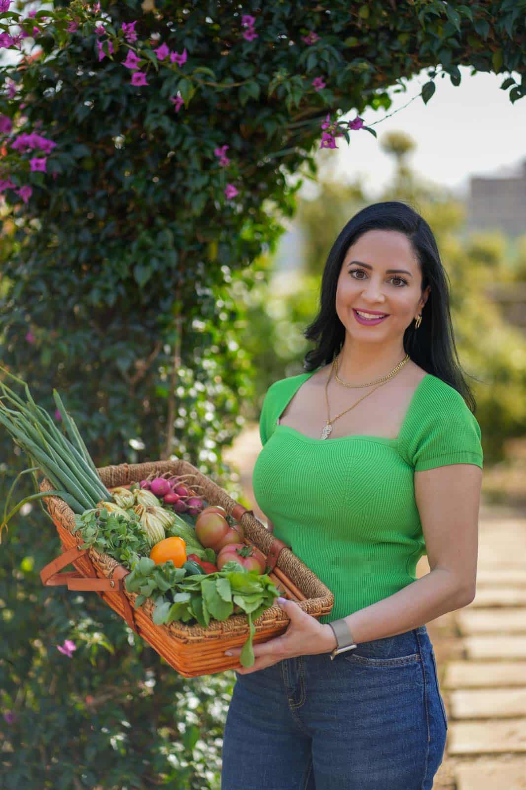 Mariam Ezzeddine, aka Mima, from cookinwithmima outdoor holding a basket of vegetables.