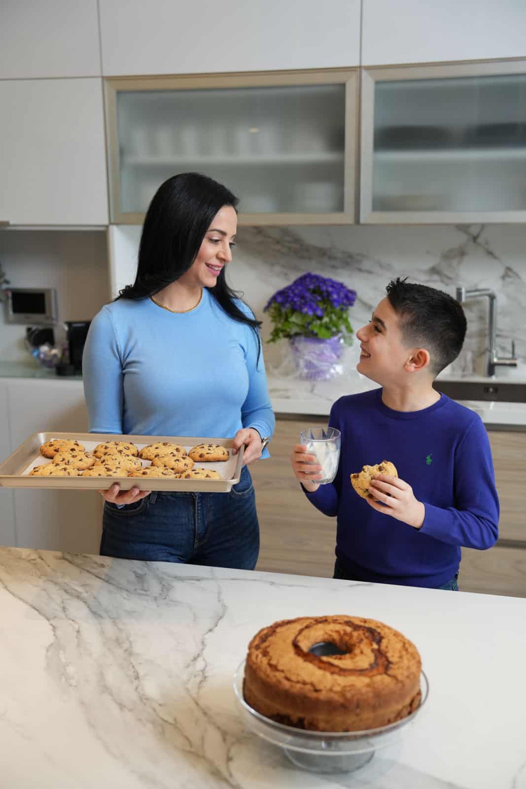Mariam Ezzeddine, aka Mima, from cookinwithmima standing next to her son in the kitchen sharing a sweet moment.