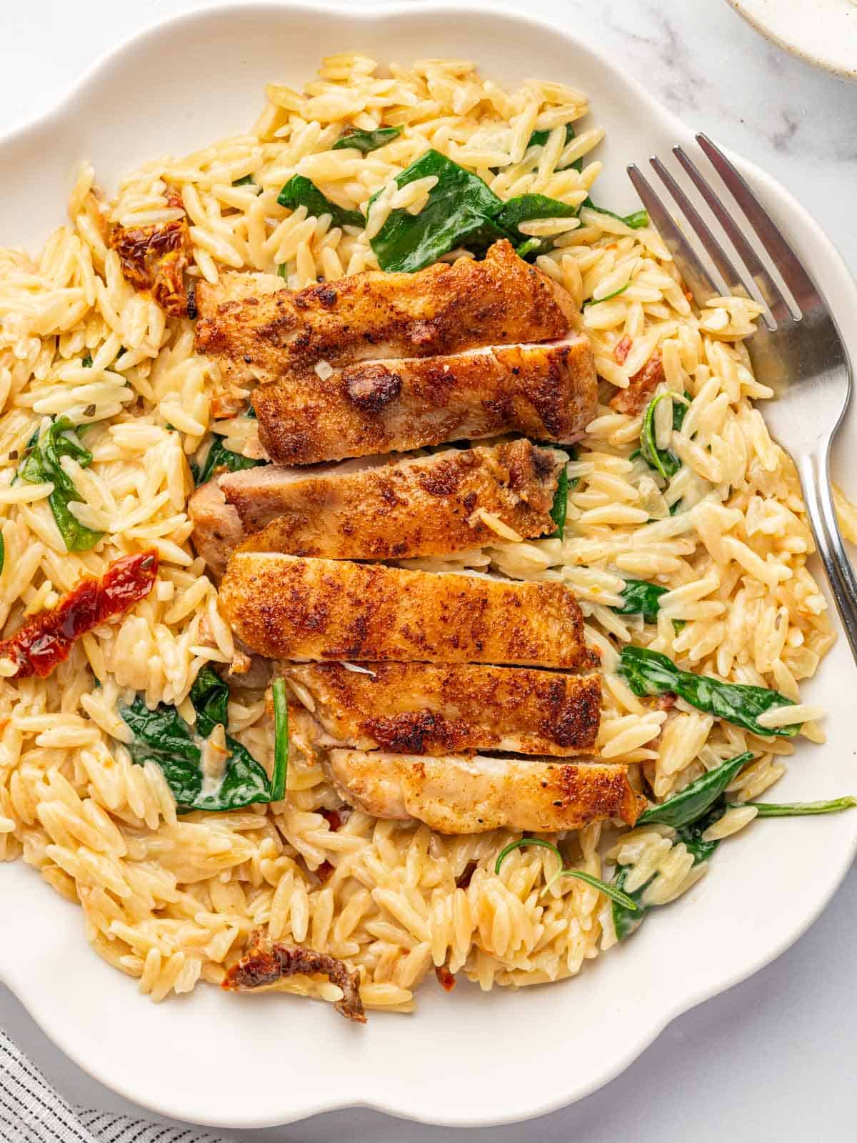 Slices of cajun chicken are served over orzo.