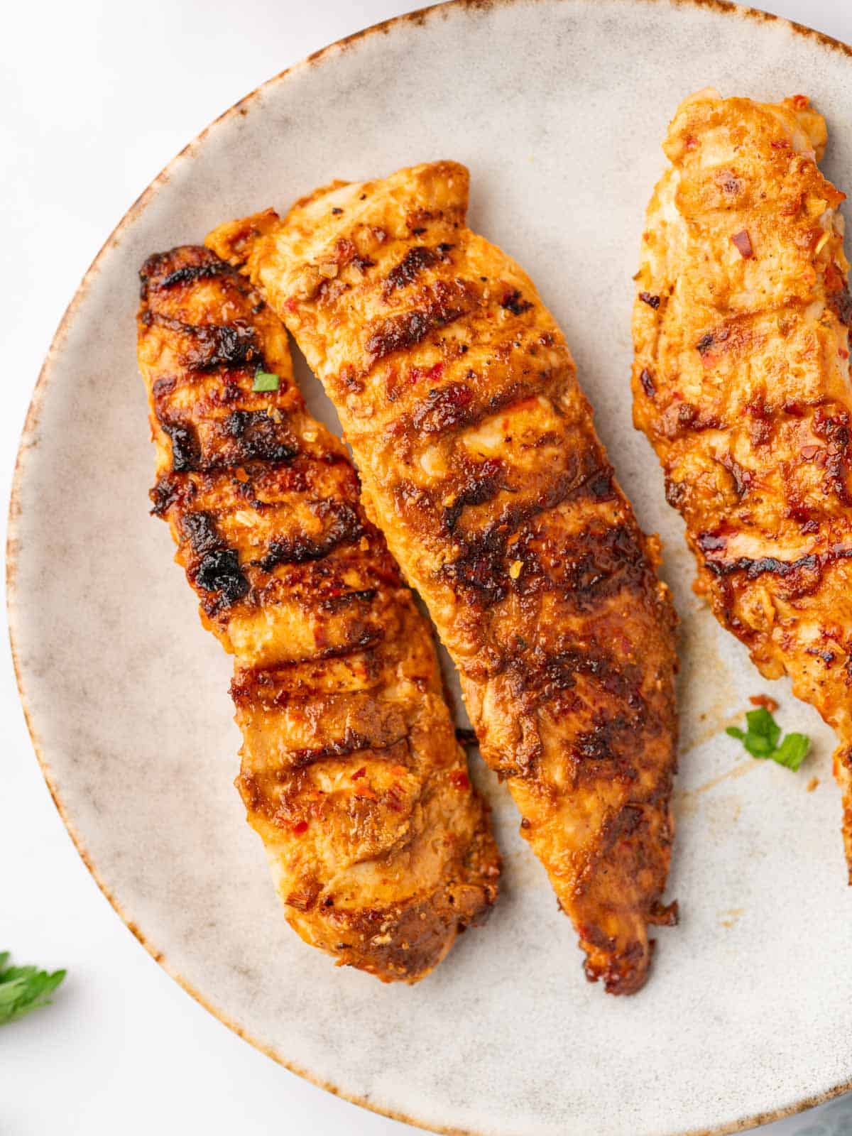 Three peri peri chicken tenders are on a plate.