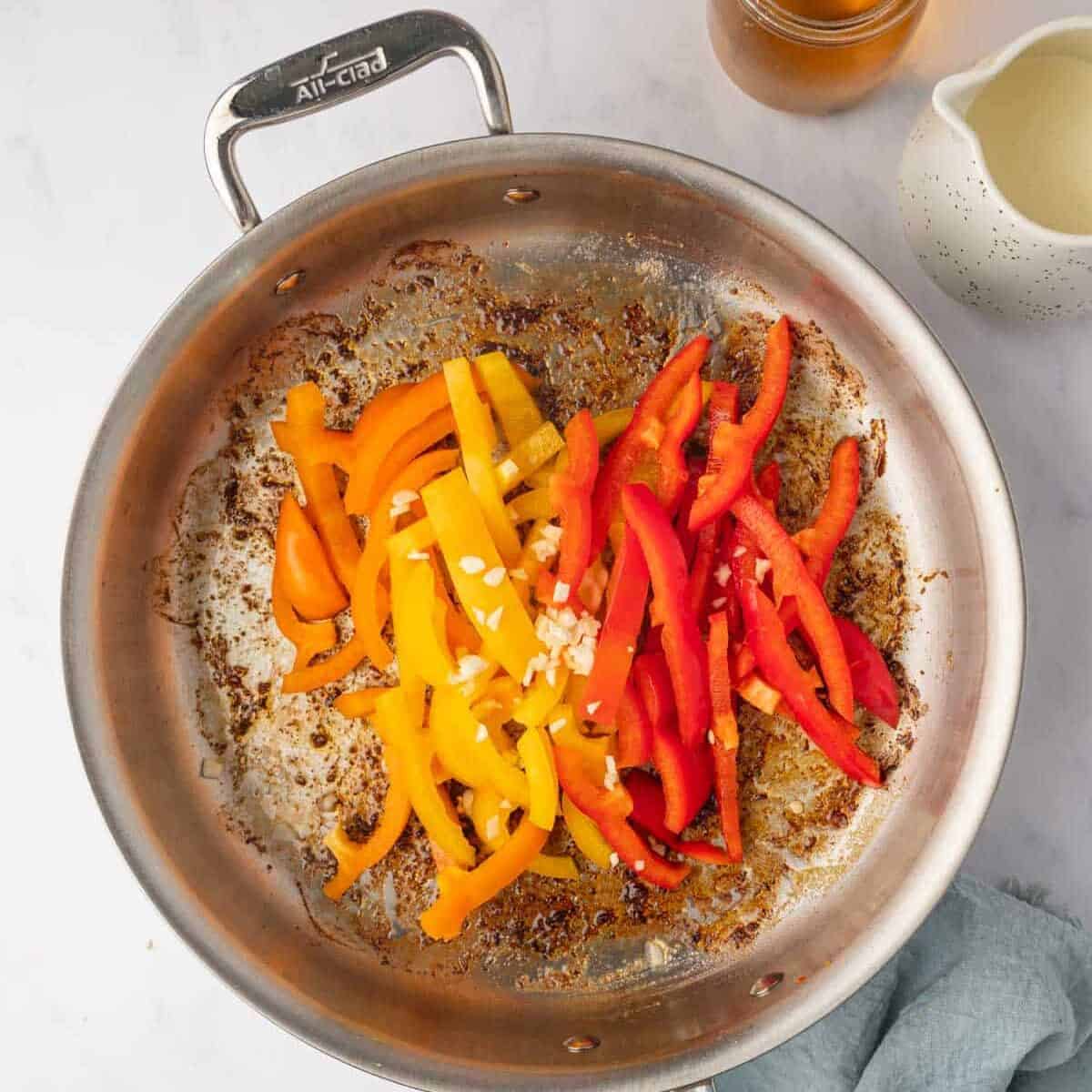 Peppers are added to a skillet to be cooked.