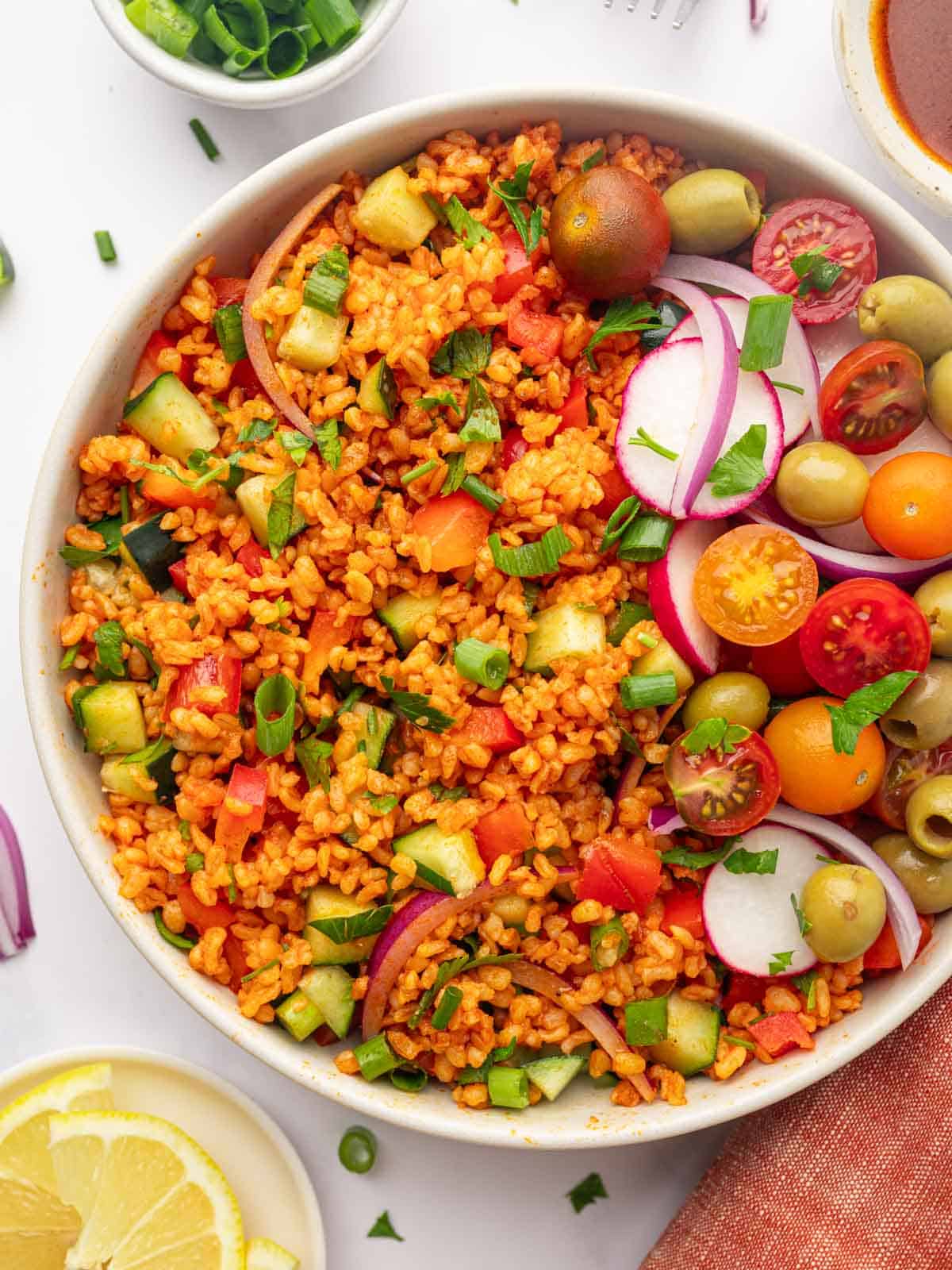Turkish Bulgur Salad (Kisir) Bowl of turkish kisir salad garnished with tomatoes, olives and radish.