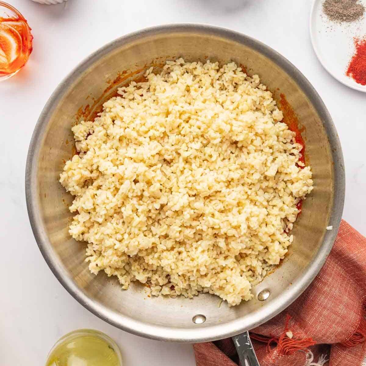 Cooked bulgur over tomato paste before mixing.